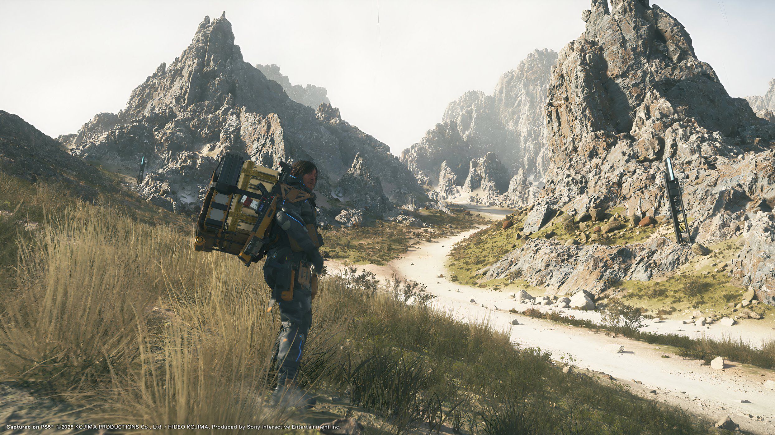 An image from the game Death Stranding 2: On The Beach, showing Sam Porter Bridges carrying a huge load on his back.