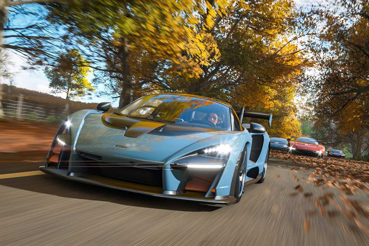 A screenshot from the game "Forza Horizon 4", showing a blue McLaren Senna racing against its competitors during fall season.
