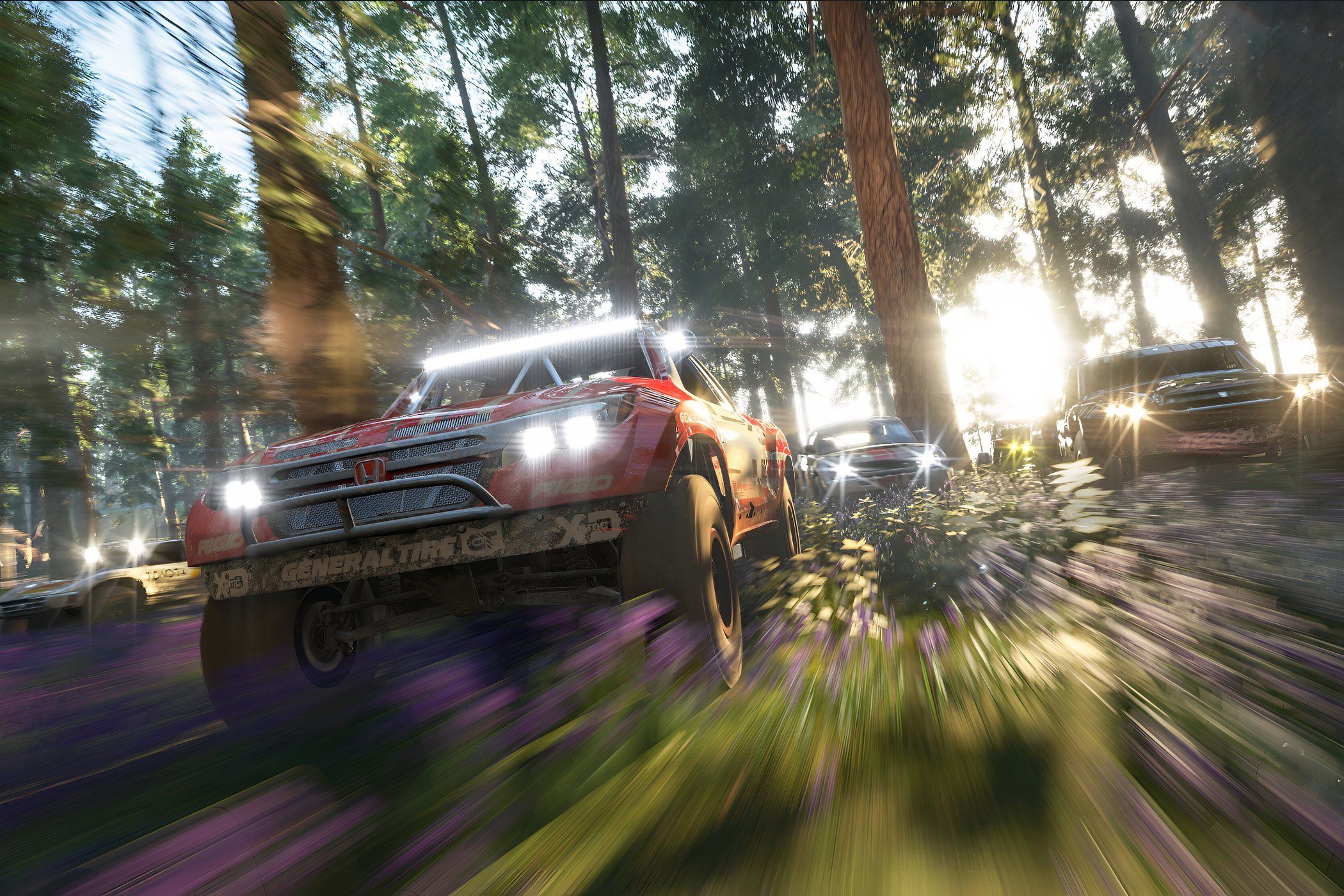 A screenshot from the game "Forza Horizon 4", showing a modifed truck racing in the forest as its competitors catch up.