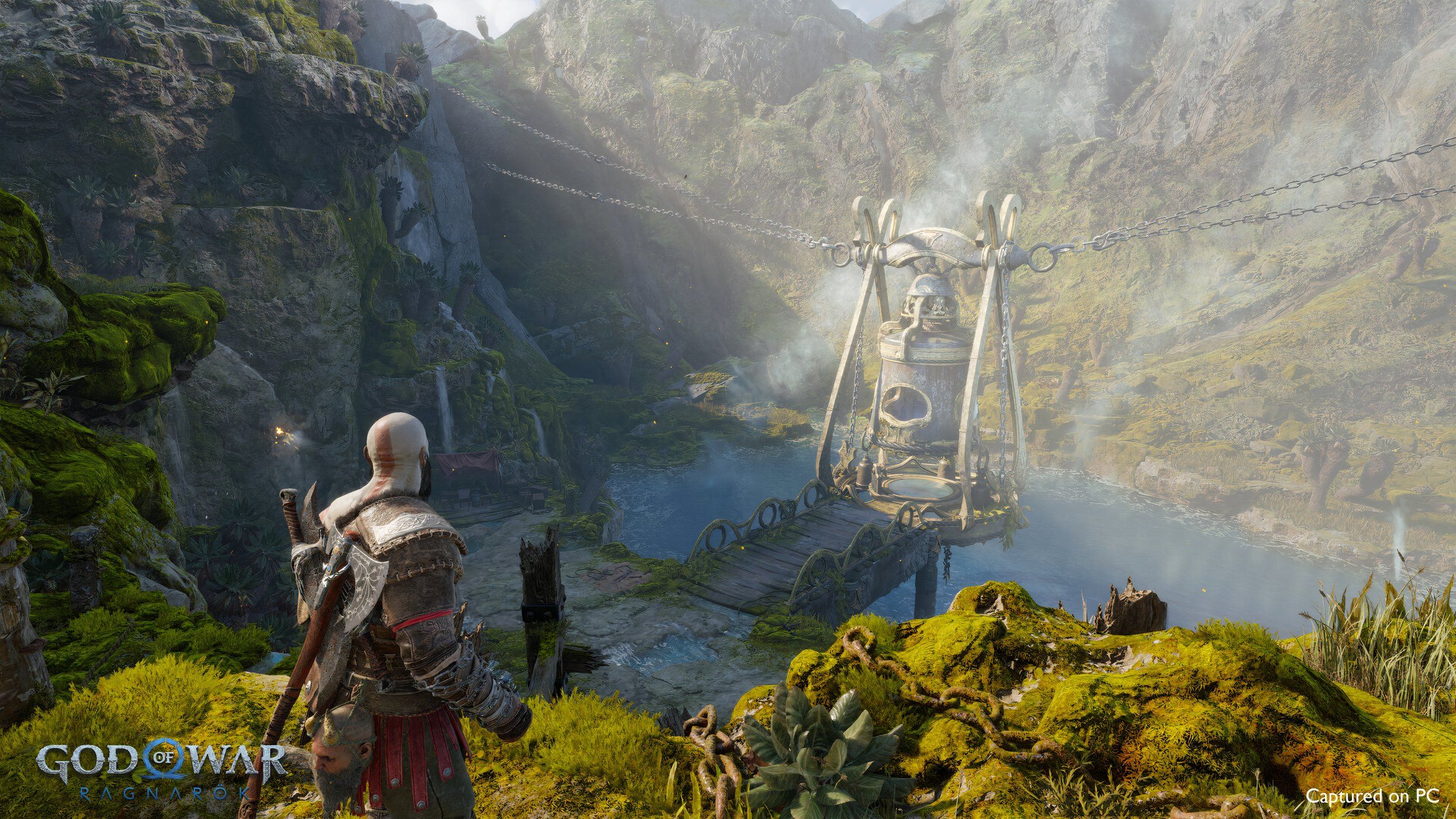 An image from the game God of War Ragnarok, showing Kratos looking at a lake nestled between mountains.