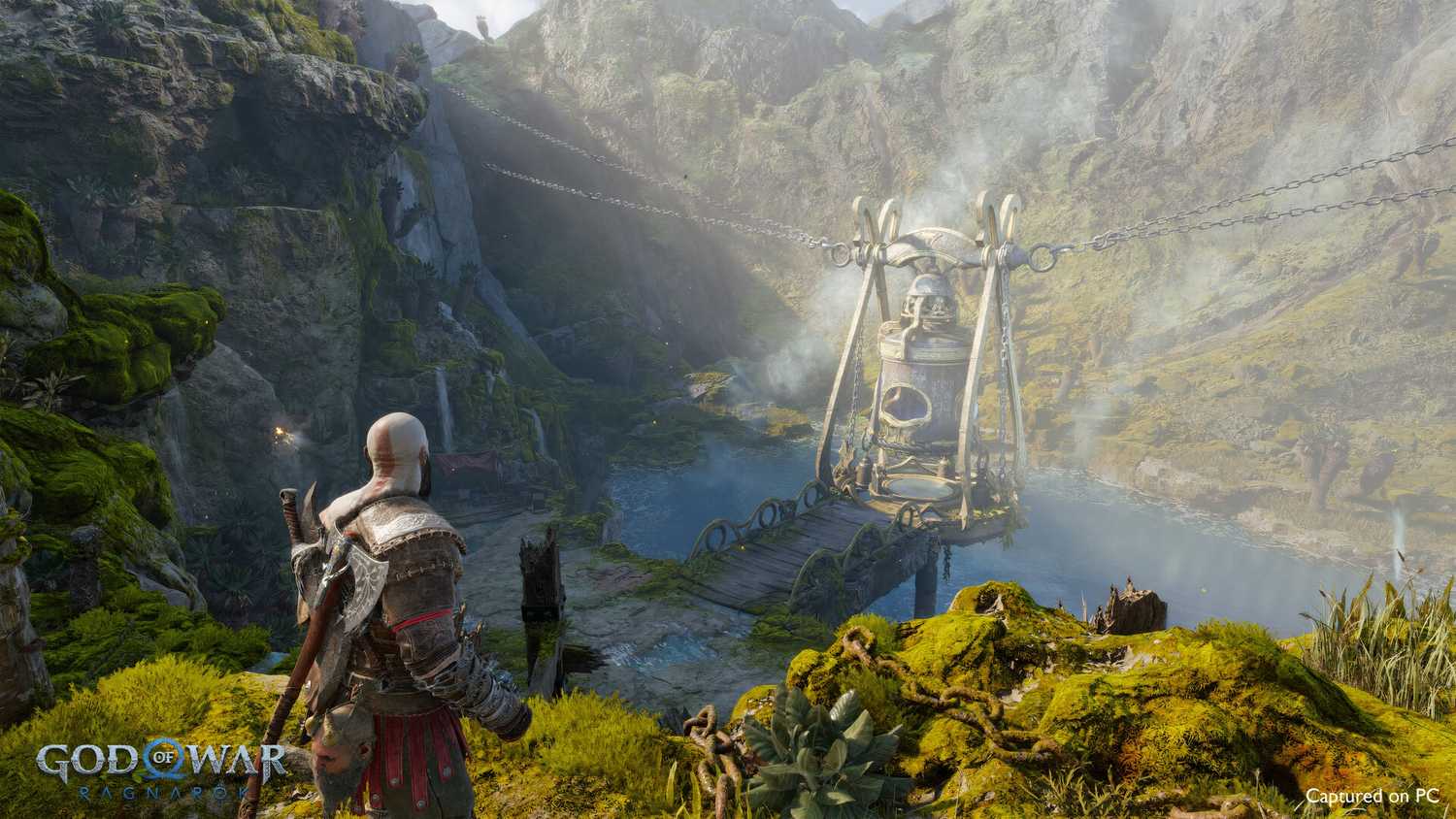 An image from the game God of War Ragnarok, showing Kratos looking at a lake nestled between mountains.