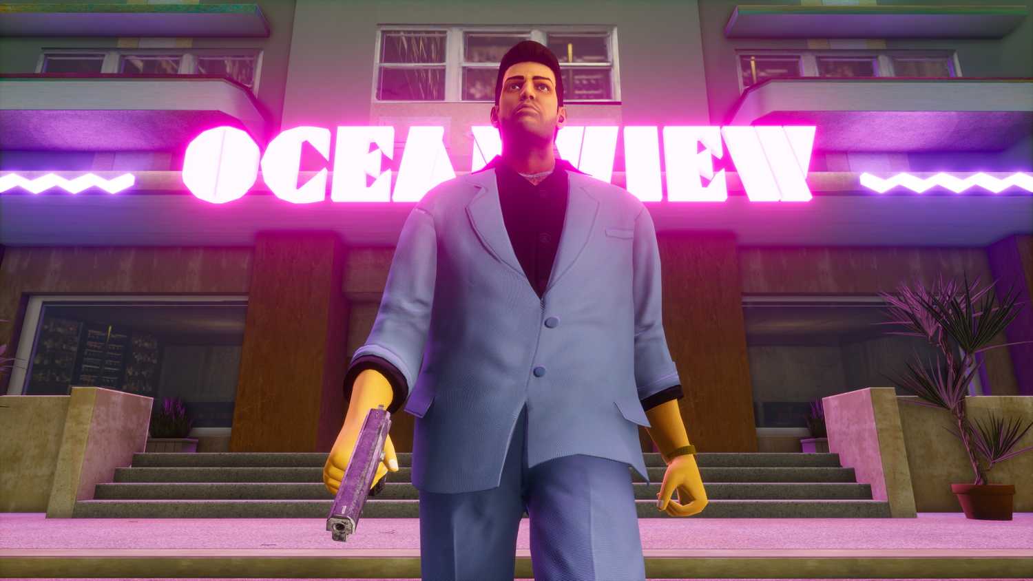 A screenshot from the game "GTA Vice City: Definitive Edition", showing Tommy Vercetti in a blue suit, walking out of the Ocean View hotel.