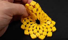 A hand holding a yellow 3D printed sunflower fabric coaster