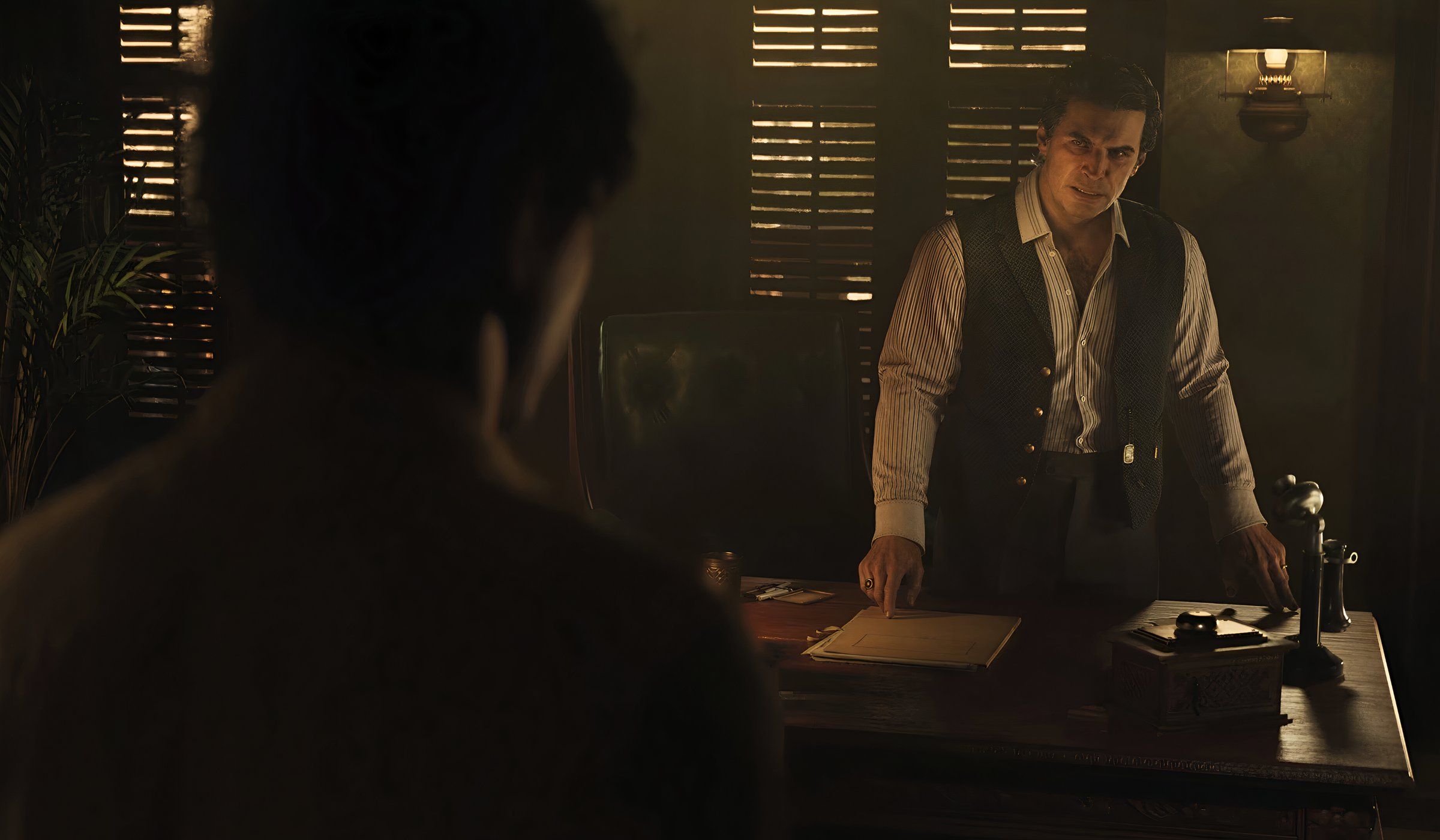 An image from the game Mafia: The Old Country, showing two men talking to each other indoors.