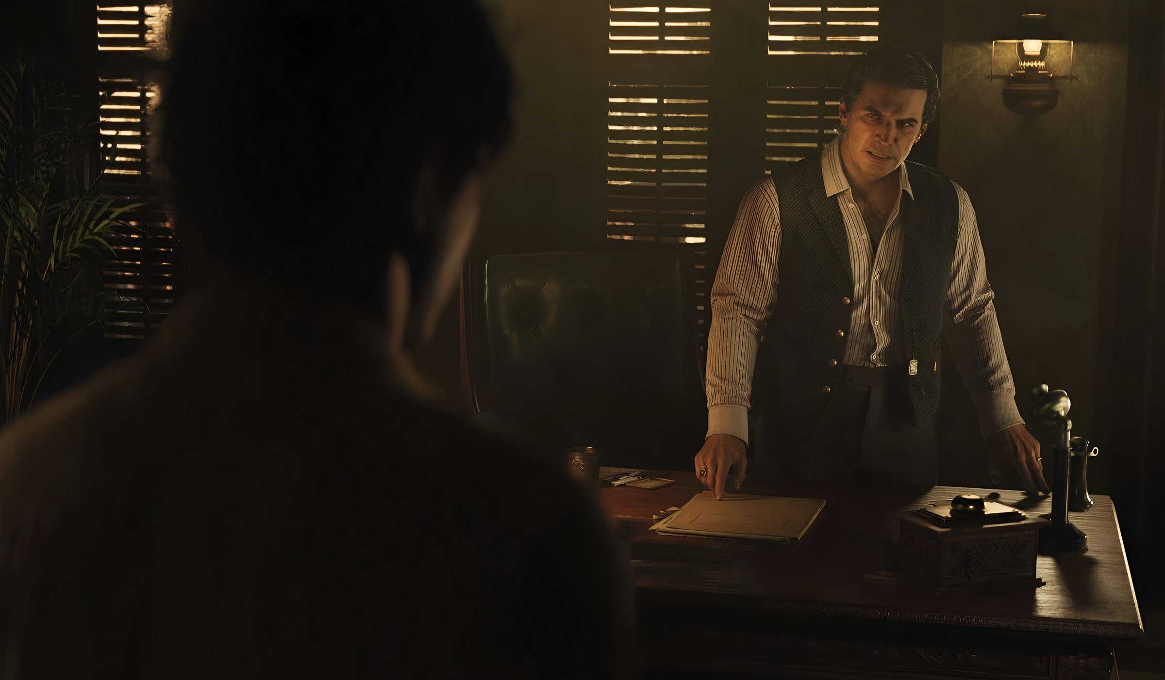 An image from the game Mafia: The Old Country, showing two men talking to each other indoors.