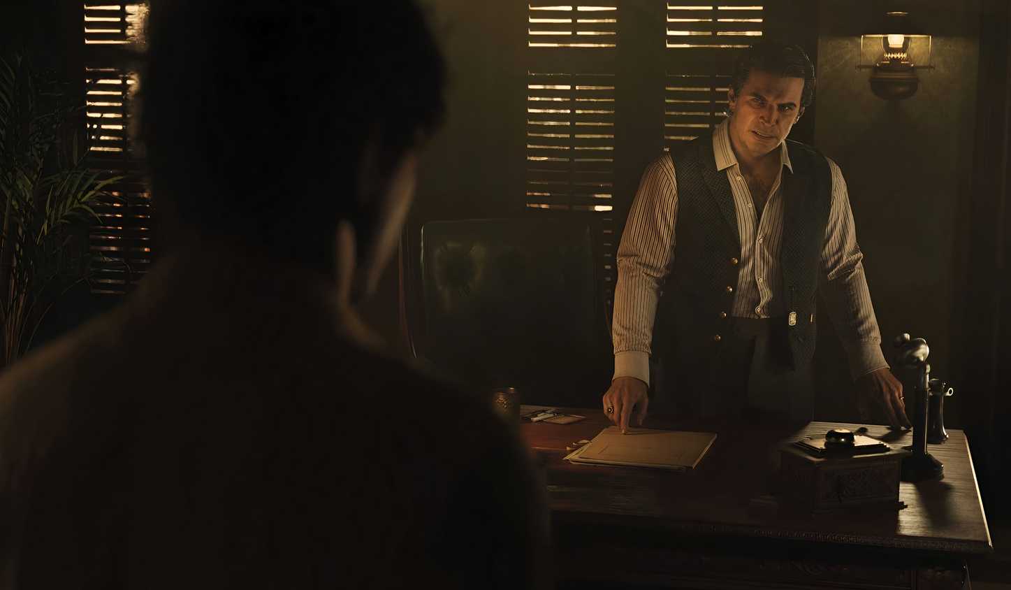 An image from the game Mafia: The Old Country, showing two men talking to each other indoors.