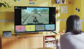A womman sitting looking at a TV displaying a Nintendo Switch 2 game with the GameChat interface