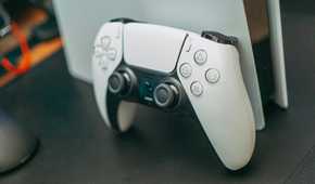 Sony's PlayStation 5 controller leaning on a PS5 console.