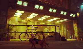 An image from the game "Stray", showing a cat running around in a yellow-lit street.