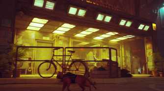 An image from the game "Stray", showing a cat running around in a yellow-lit street.