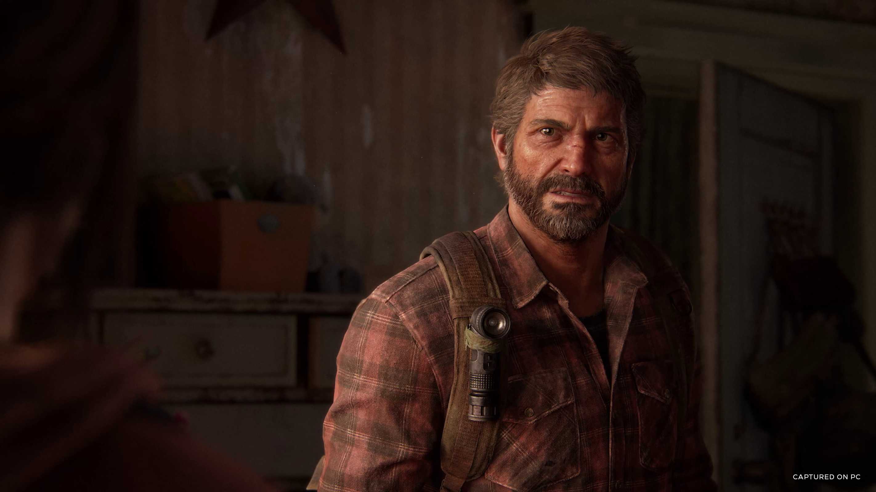 A screenshot from The Last of Us Part I on PC, showing Joel wearing a red flannel shirt.