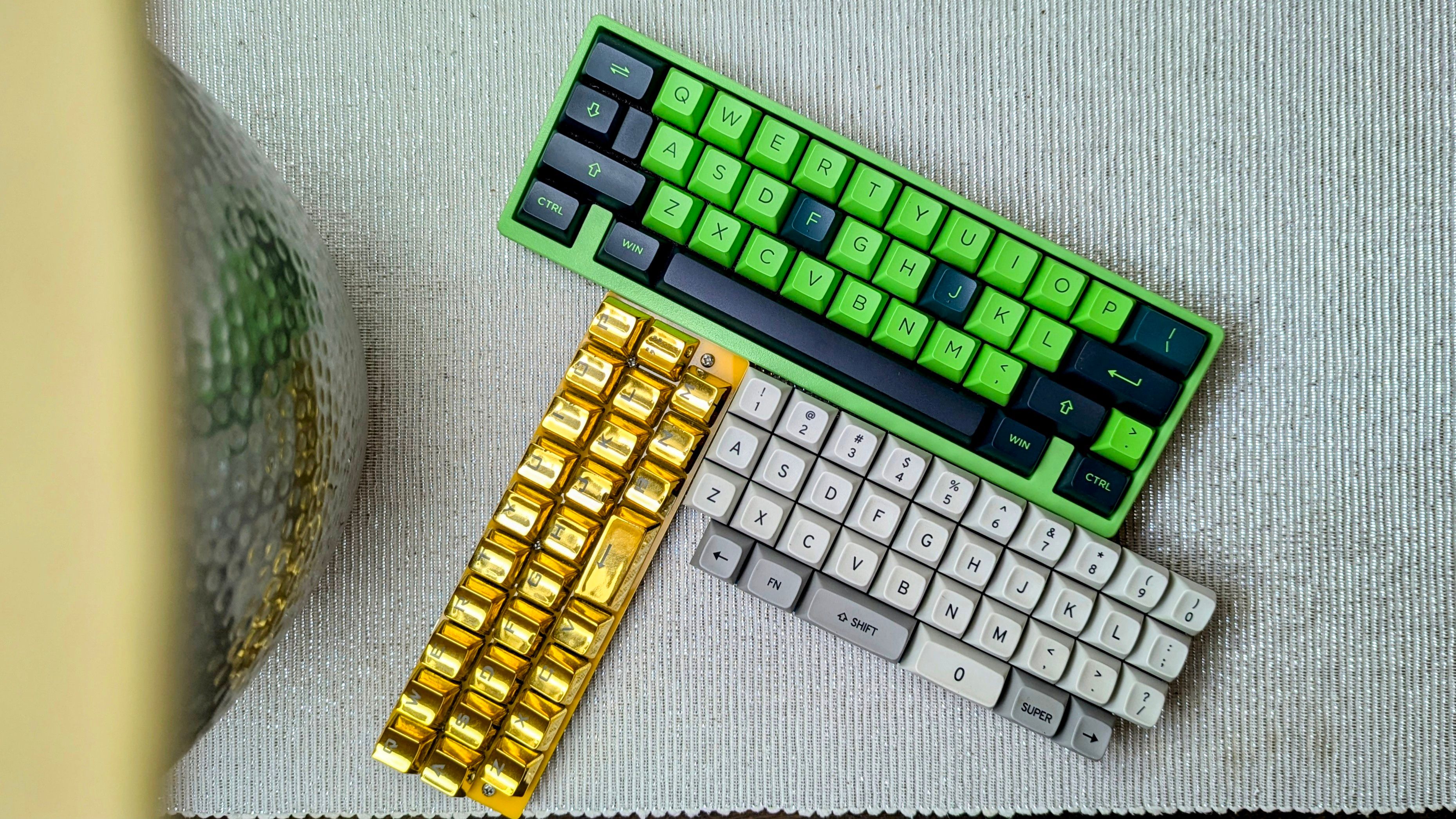 A green, golden, and white mini mechanical keyboard on a textured white tabletop