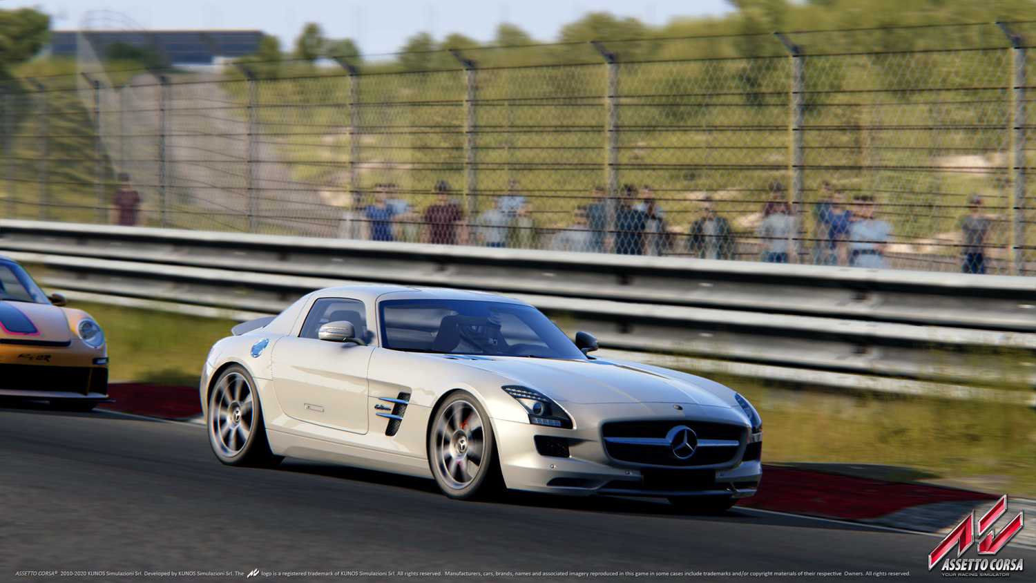 A screenshot from the game "Assetto Corsa", showing a silver Mercedes-AMG car racing on the track as viewers look on at the sidelines.