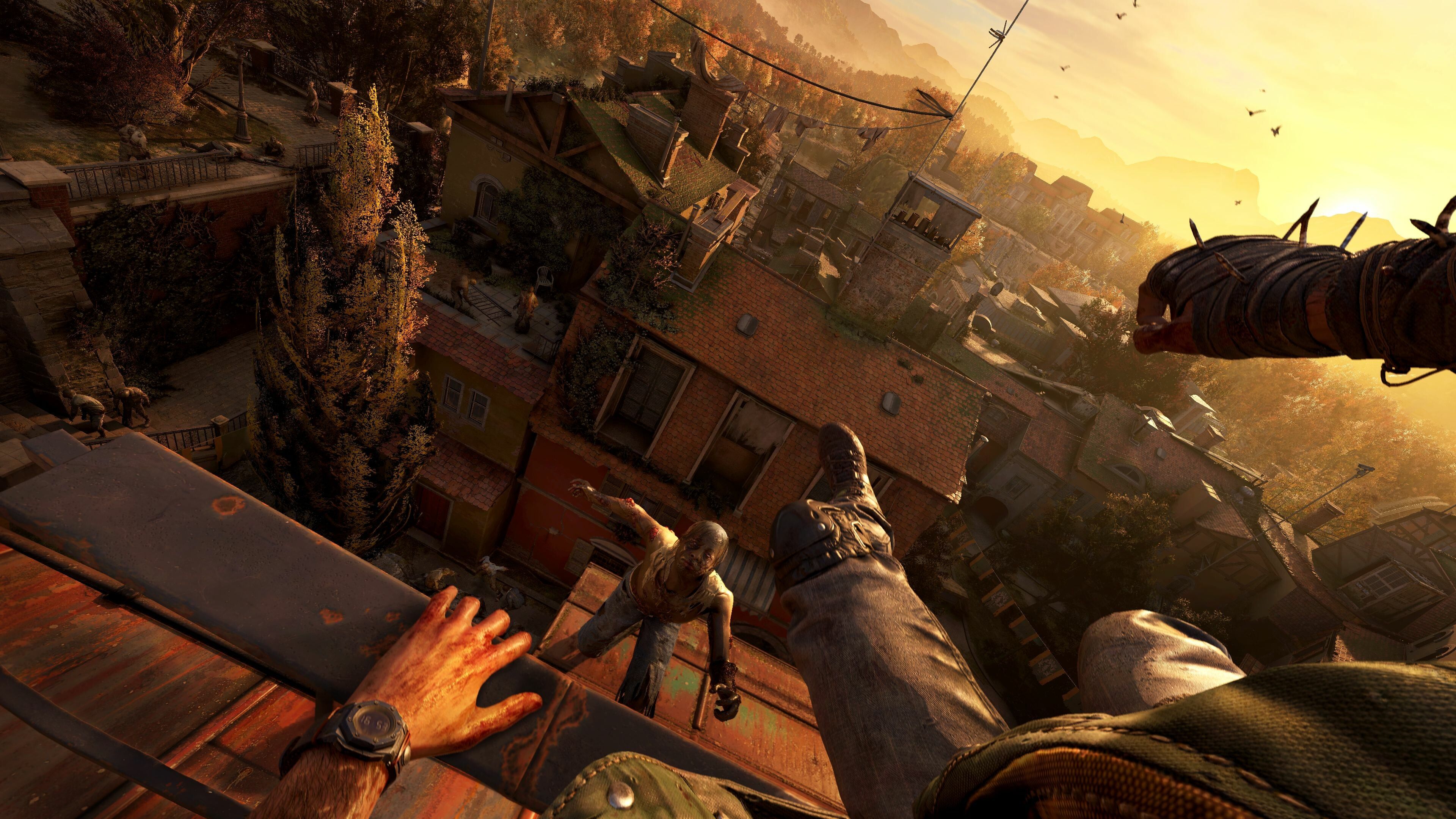 the sun setting while the player character parkours over a ledge towards a shambling zombie on a rooftop.