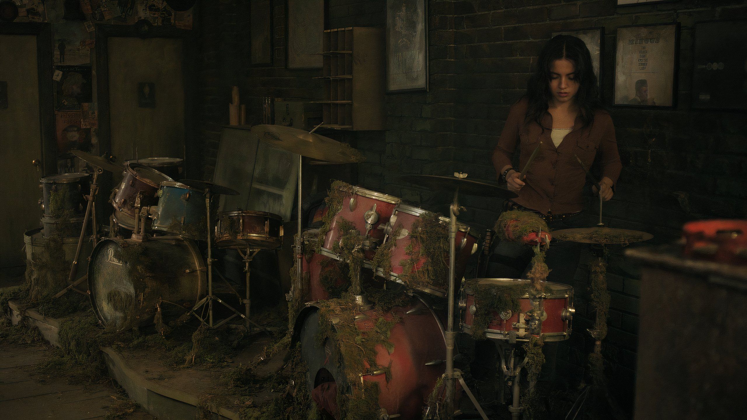 A screengrab from episode 4 of the HBO show The Last of Us Season 2, showing Dina playing the drums inside a music shop.