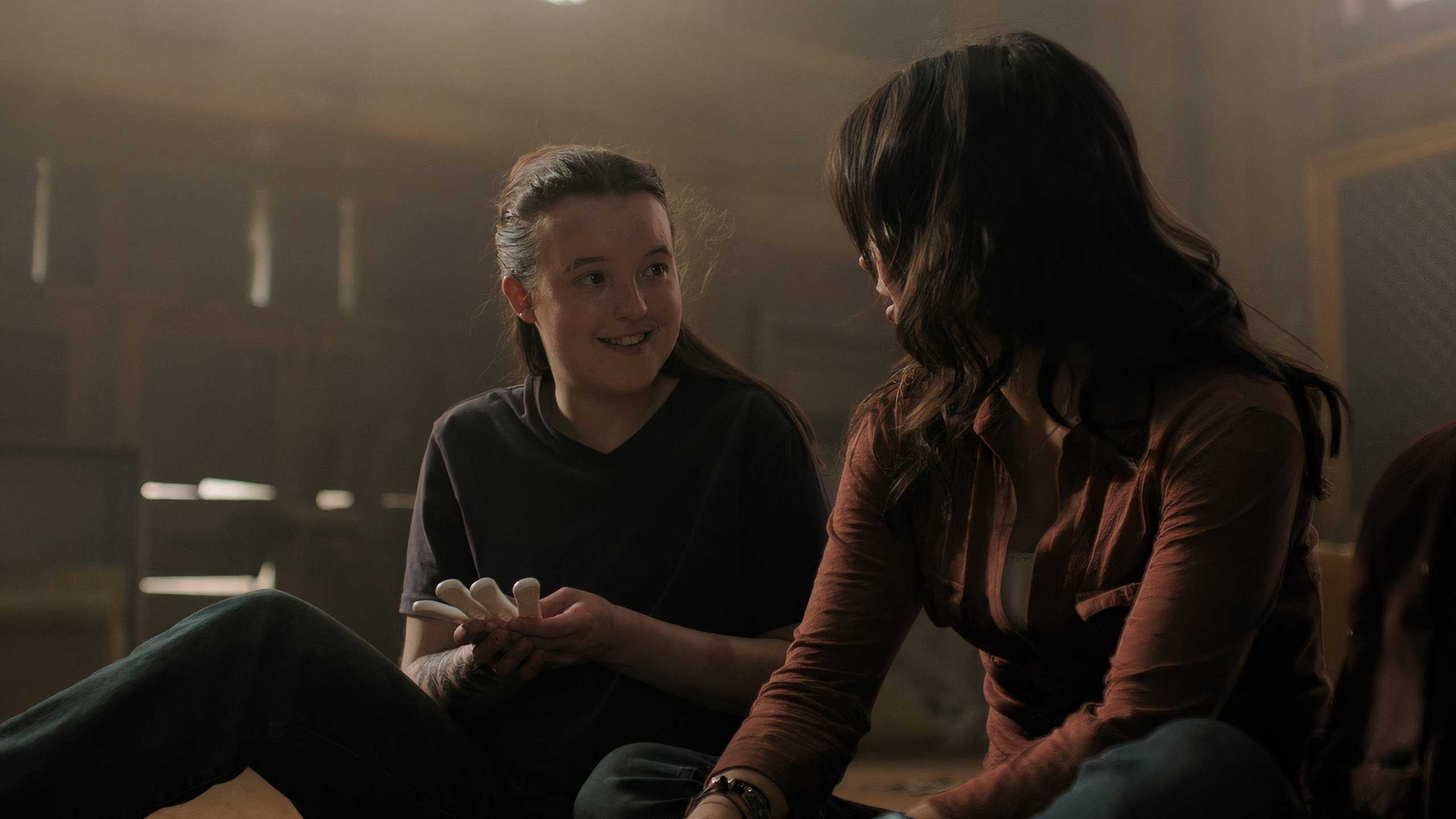 A screengrab from episode 4 of the HBO show The Last of Us Season 2, showing Ellie and Dina smiling at each other.