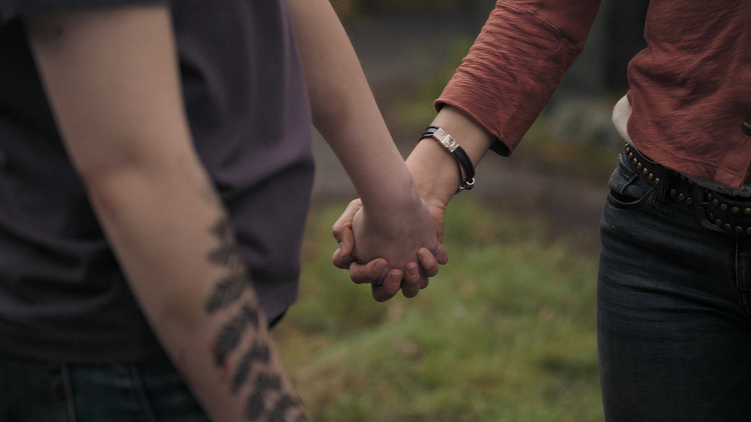 A screengrab from episode 4 of the HBO show The Last of Us Season 2, showing Ellie and Dina holding hands.