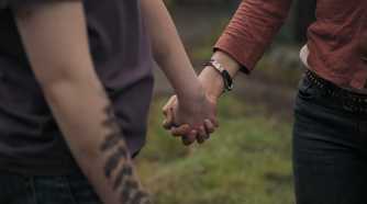 A screengrab from episode 4 of the HBO show The Last of Us Season 2, showing Ellie and Dina holding hands.