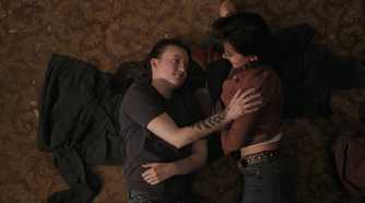 A screengrab from episode 4 of the HBO show The Last of Us Season 2, showing Ellie and Dina lying on the ground together.