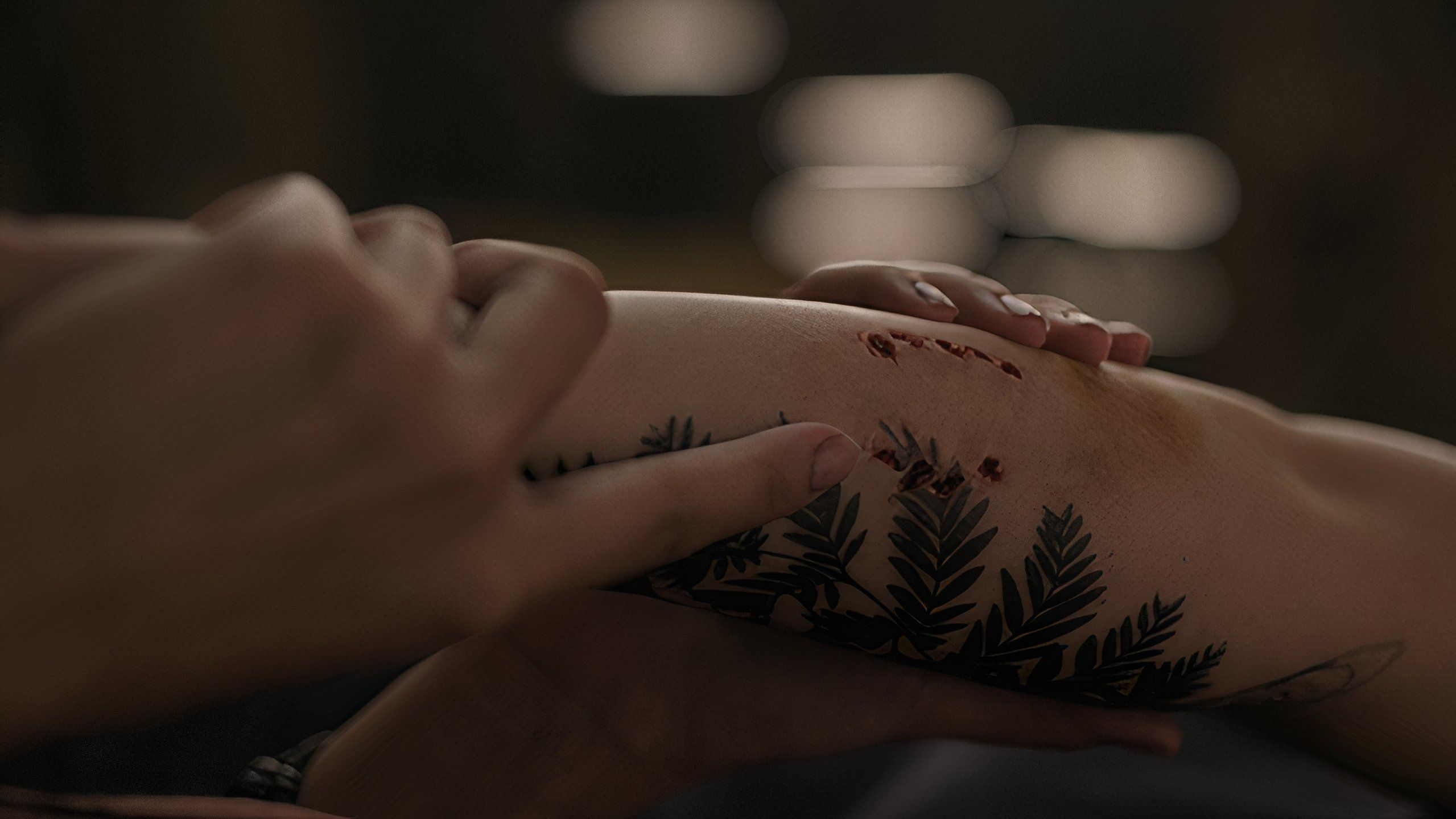 A screengrab from episode 4 of the HBO show The Last of Us Season 2, showing Dina's hands holding Ellie's arm, with a tattoo and bite mark visible on the latter.