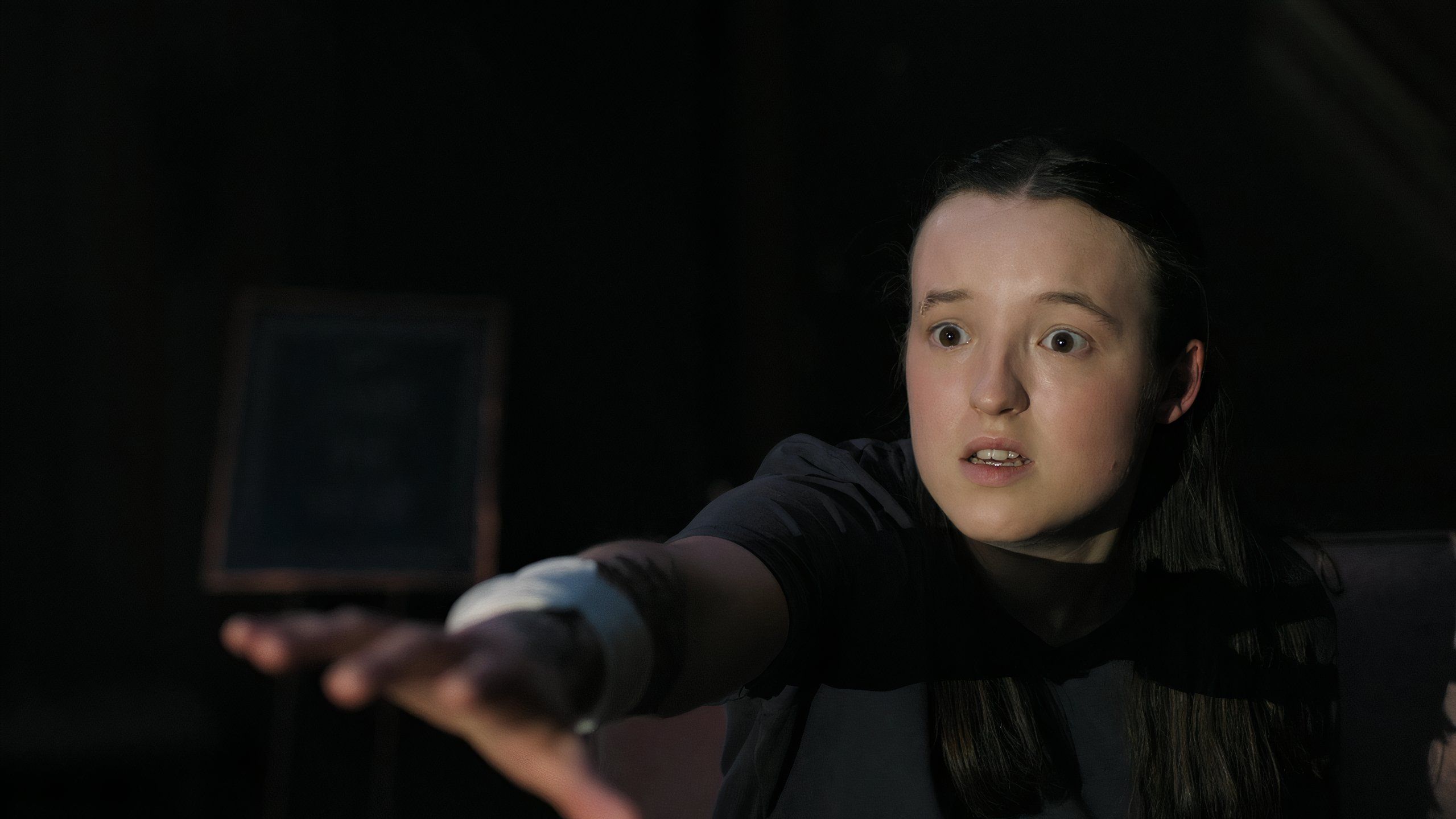 A screengrab from episode 4 of the HBO show The Last of Us Season 2, showing Ellie raising her arm out with a terrified look on her face.