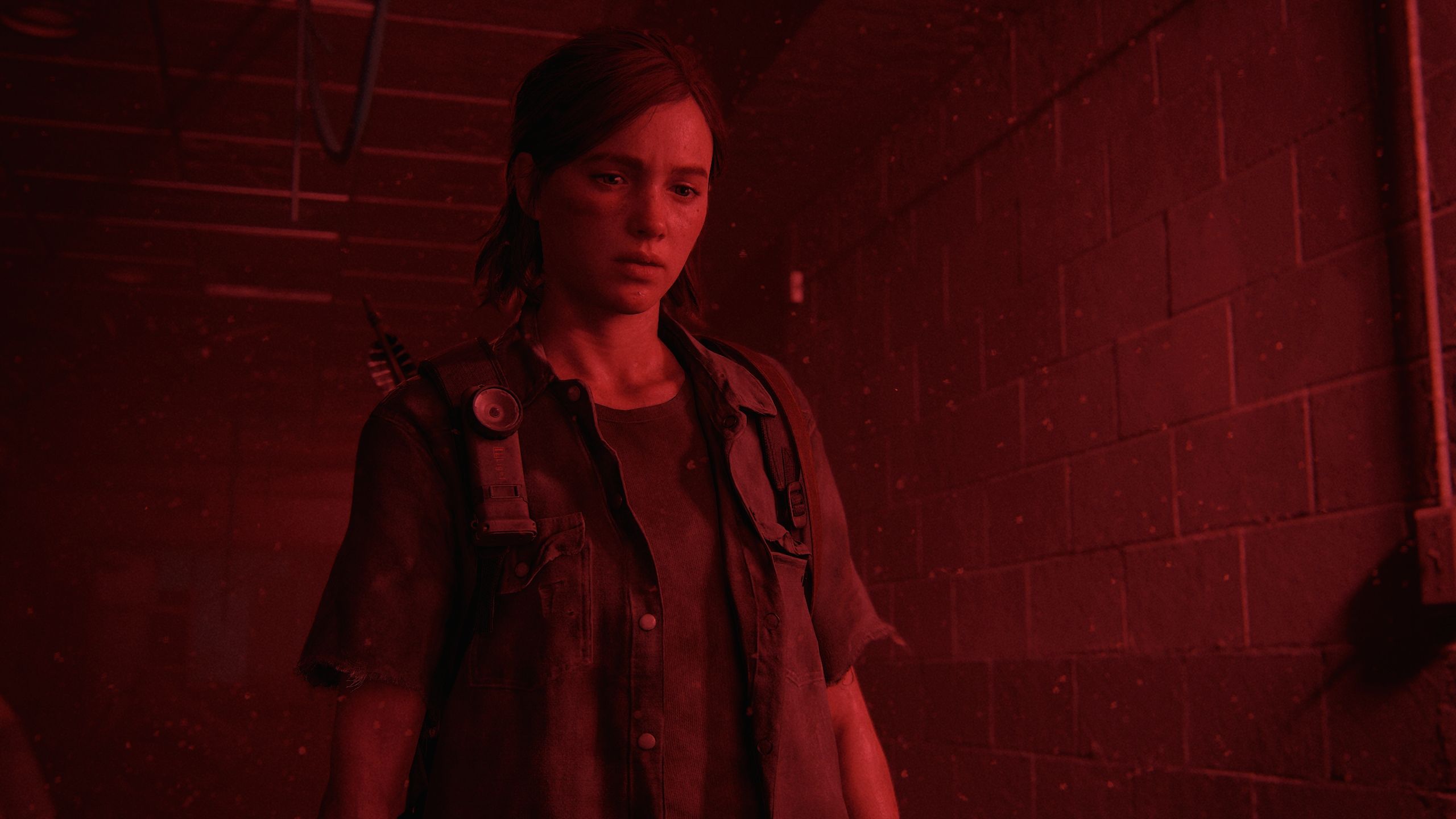 Ellie looking angry in a red-lit hallway in The Last of Us Part II.
