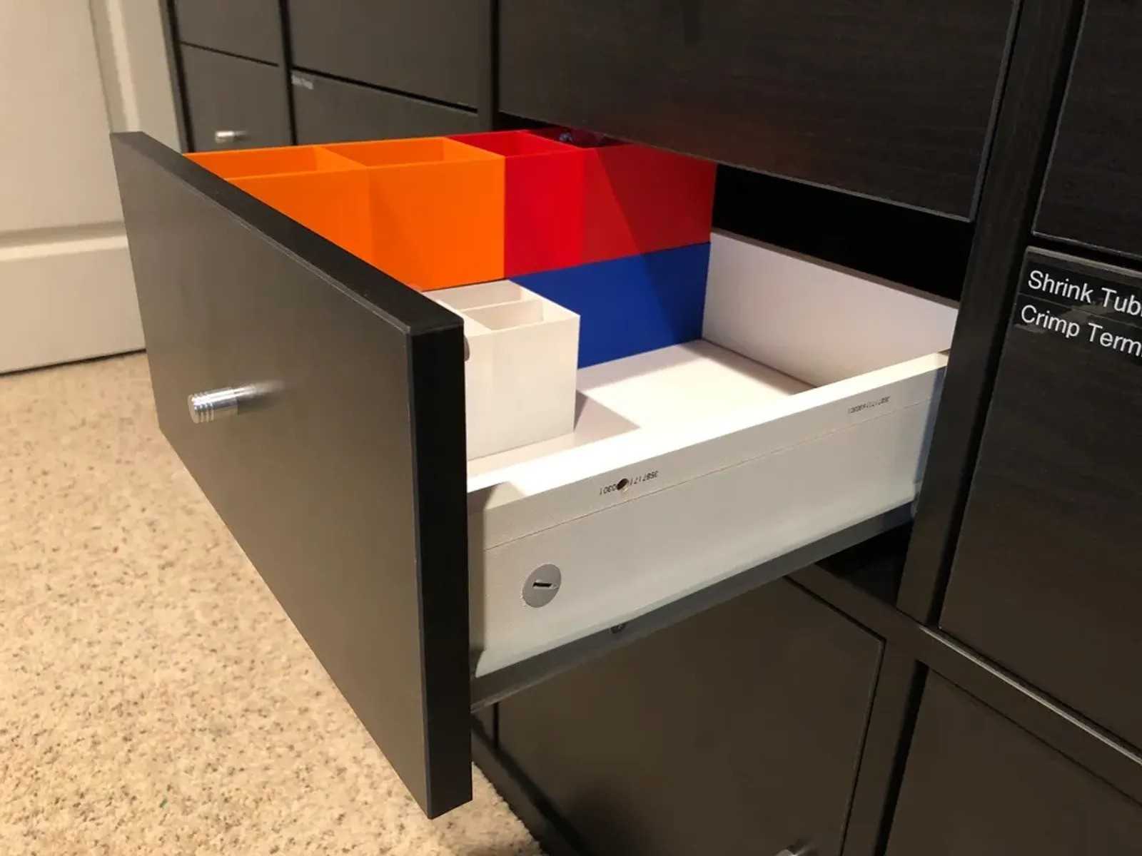 A black IKEA Kallax drawer with colorful 3D printed plastics