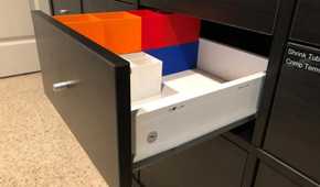 A black IKEA Kallax drawer with colorful 3D printed plastics
