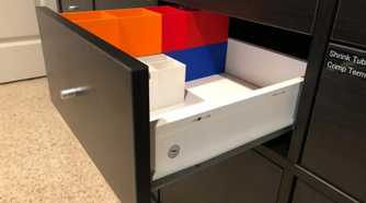 A black IKEA Kallax drawer with colorful 3D printed plastics