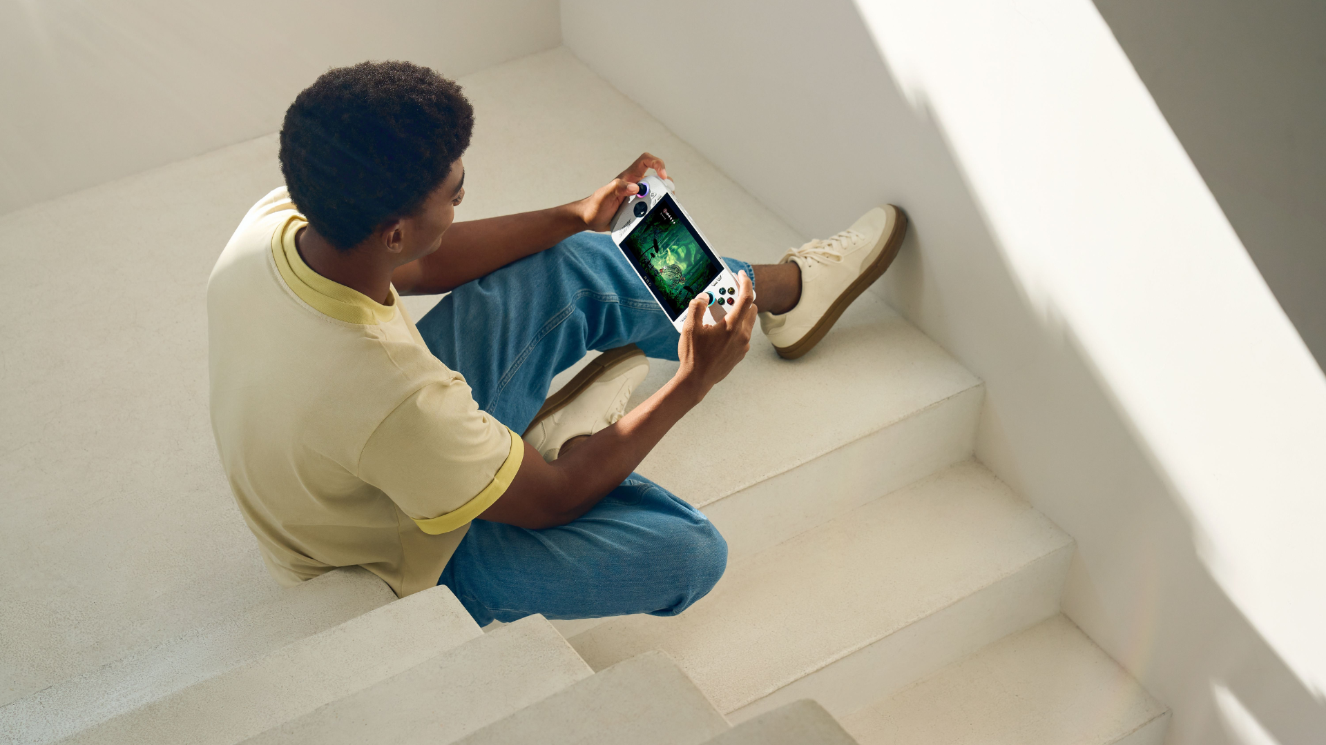 A man playing on the Xbox Ally in a stairwell