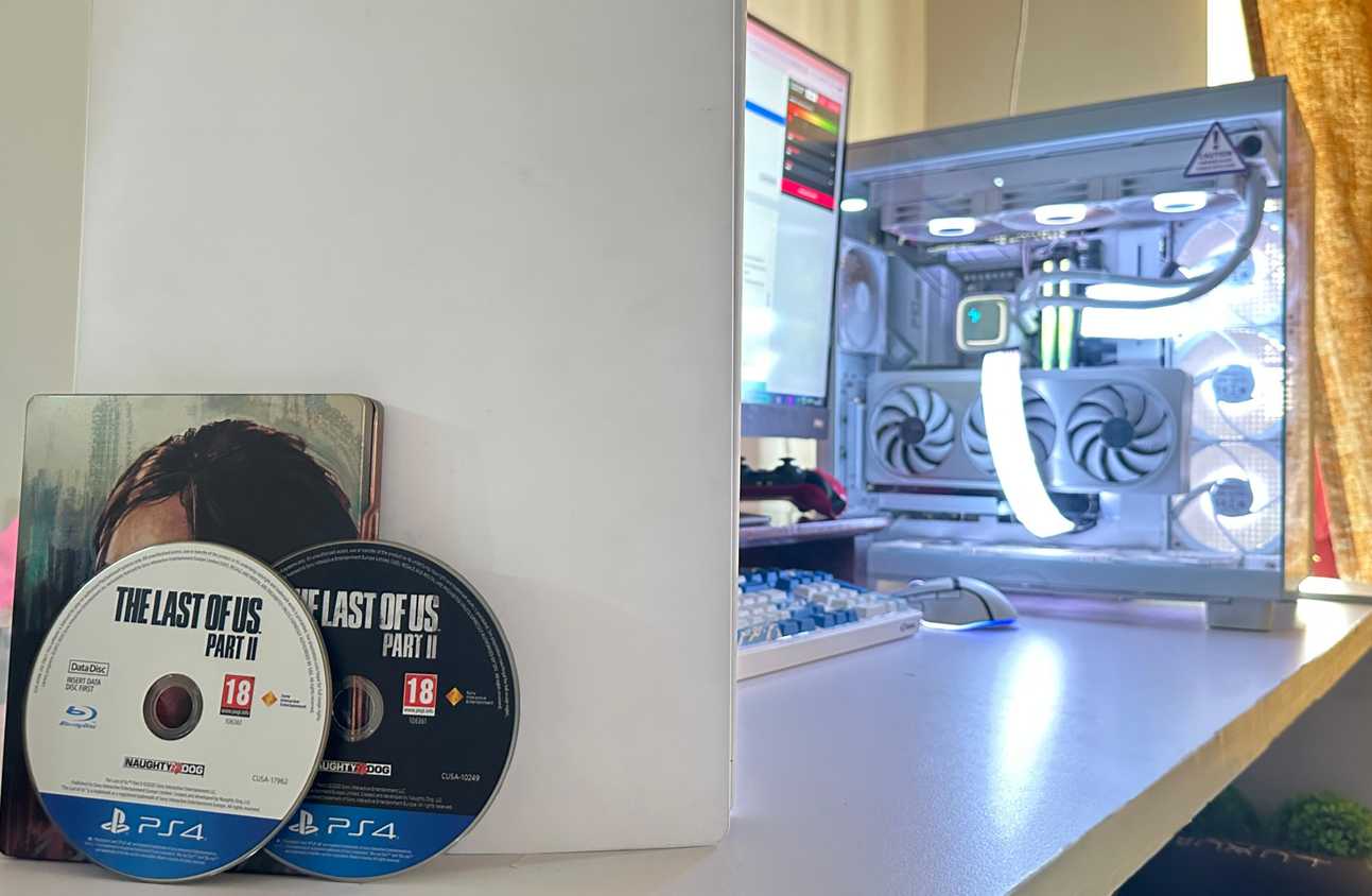 Two discs for The Last of Us Part II PS4 version, next to a PC and a PS5.