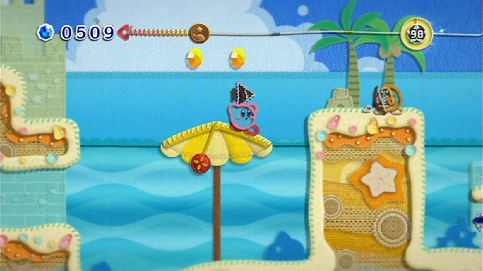 A screenshot of Kirby on a beach during gameplay from Kirby's Epic Yarn
