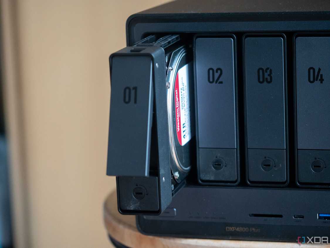 Ugreen four-bay NAS resting on a table with one bay open