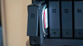 Ugreen four-bay NAS resting on a table with one bay open