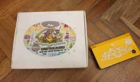 The box and console of a A folded yellow Nintendo DSi XL from the 2010 Pokemon World Championships.