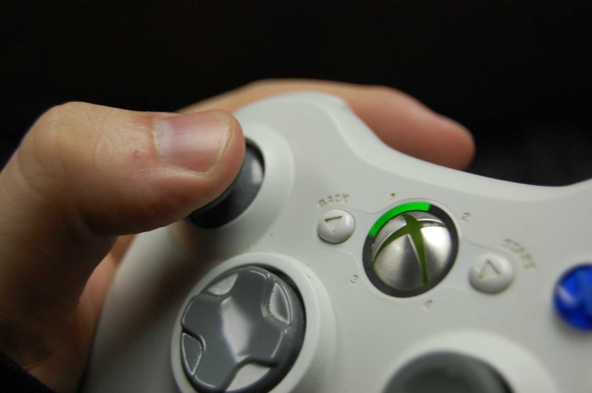 A hand holding an Xbox 360 controller in white.