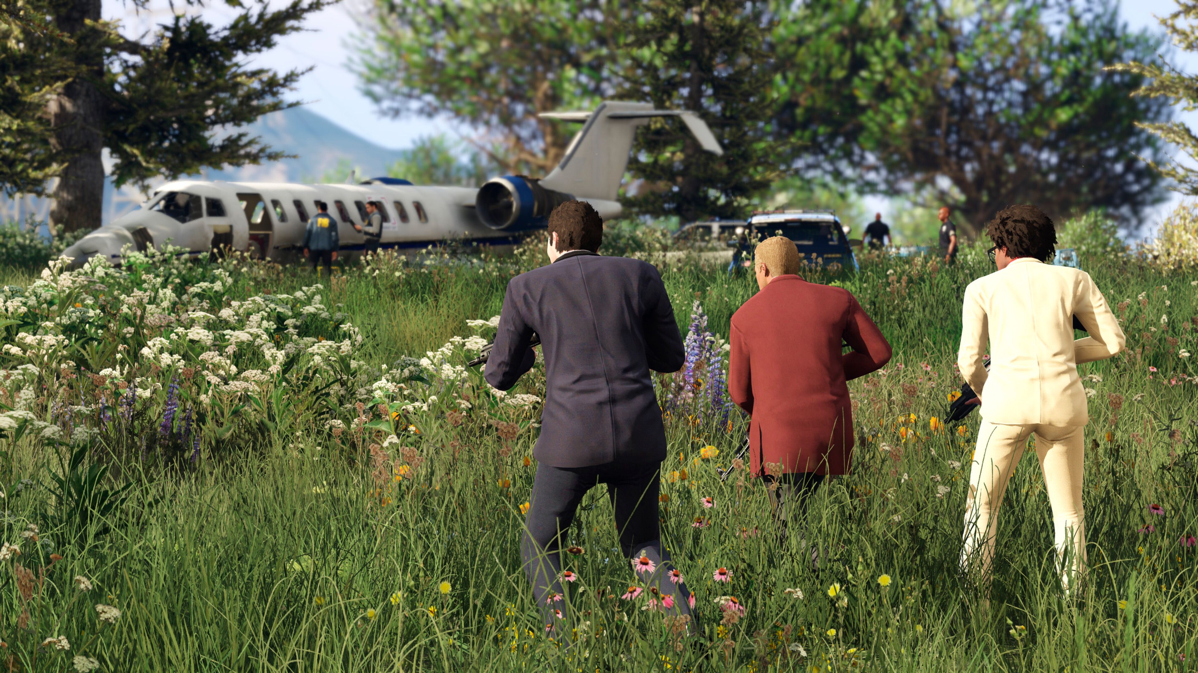 Three people crouching and holding weapons, walking through a grassy field in GTA V.