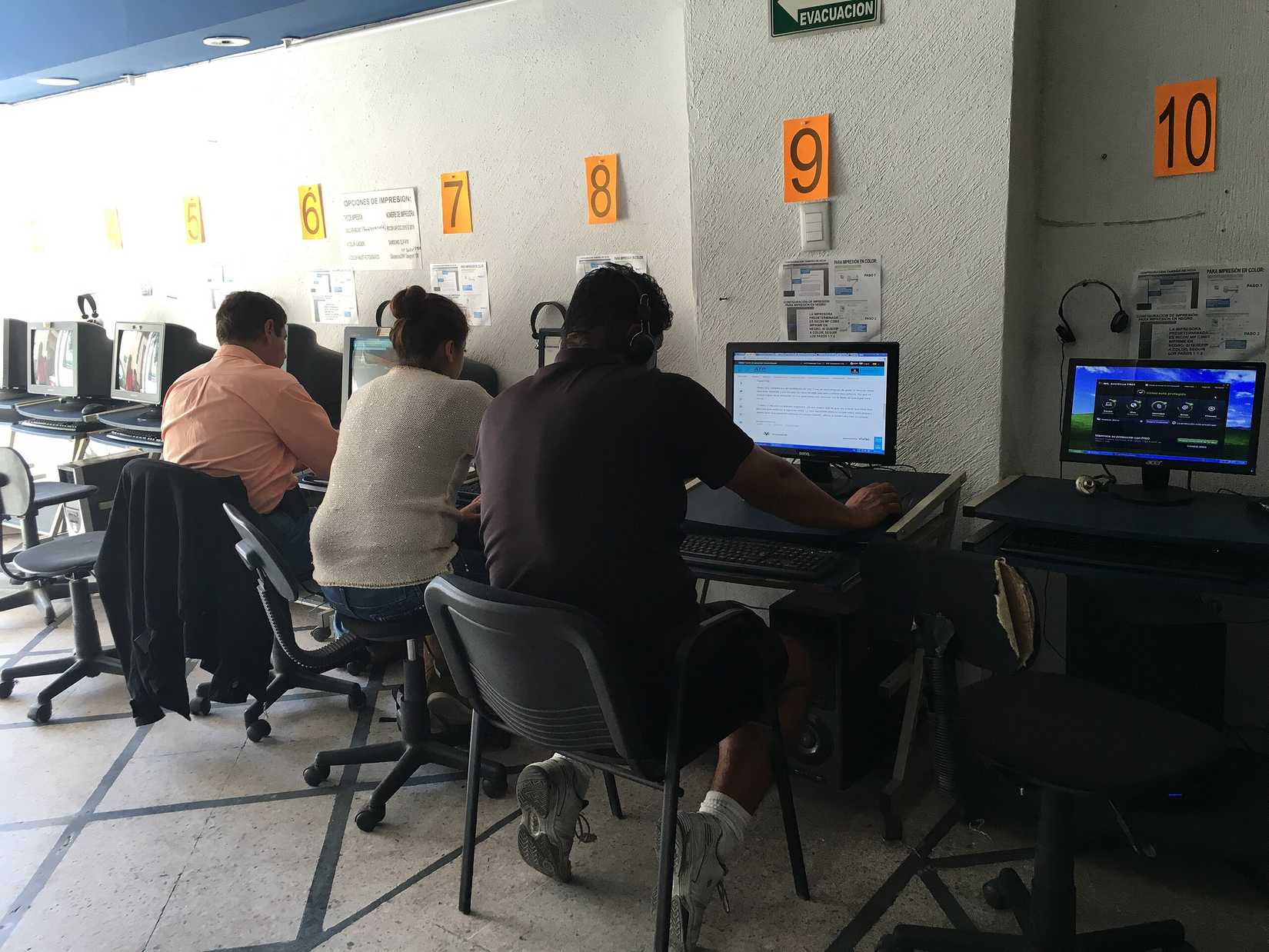 Tres personas sentadas en un cibercafé.
