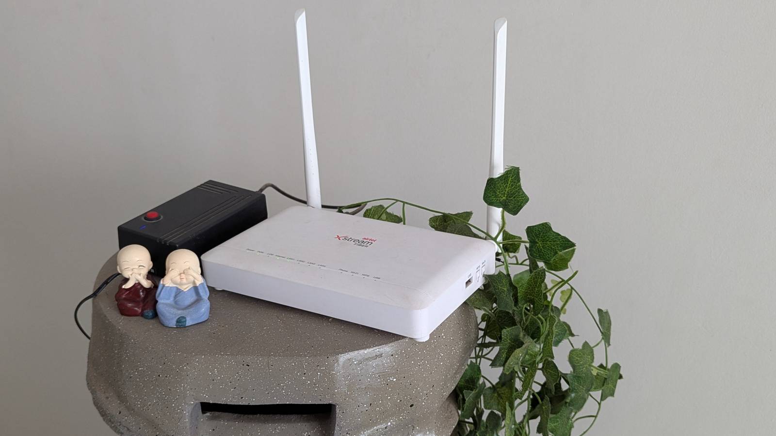 A white router on a stand next to green leaves