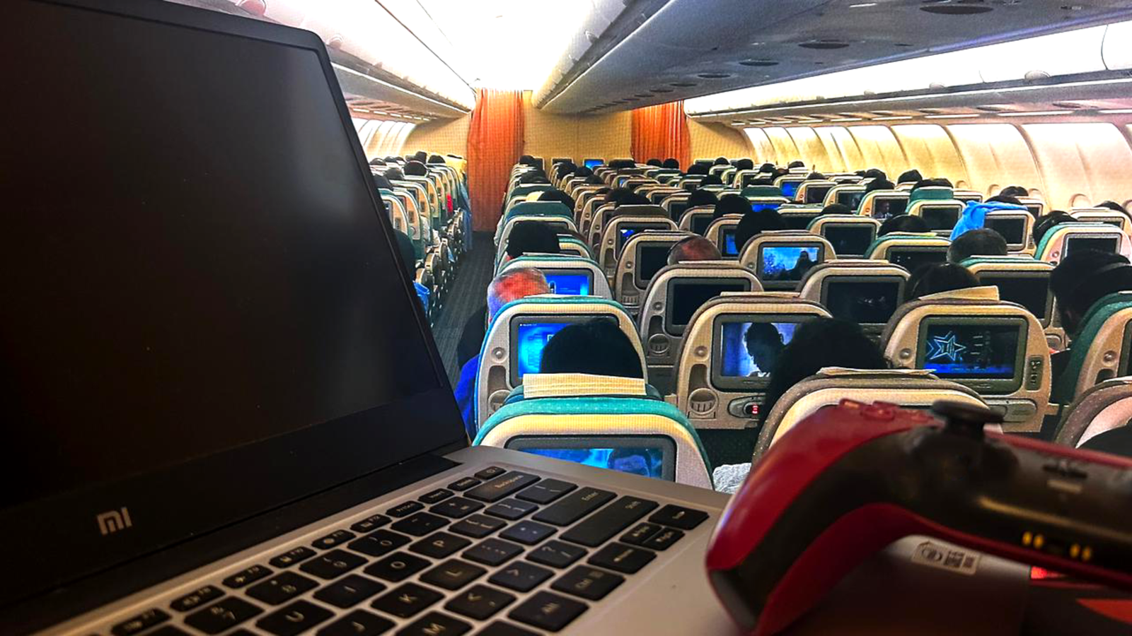 A laptop with a controller in an airplane cabin.