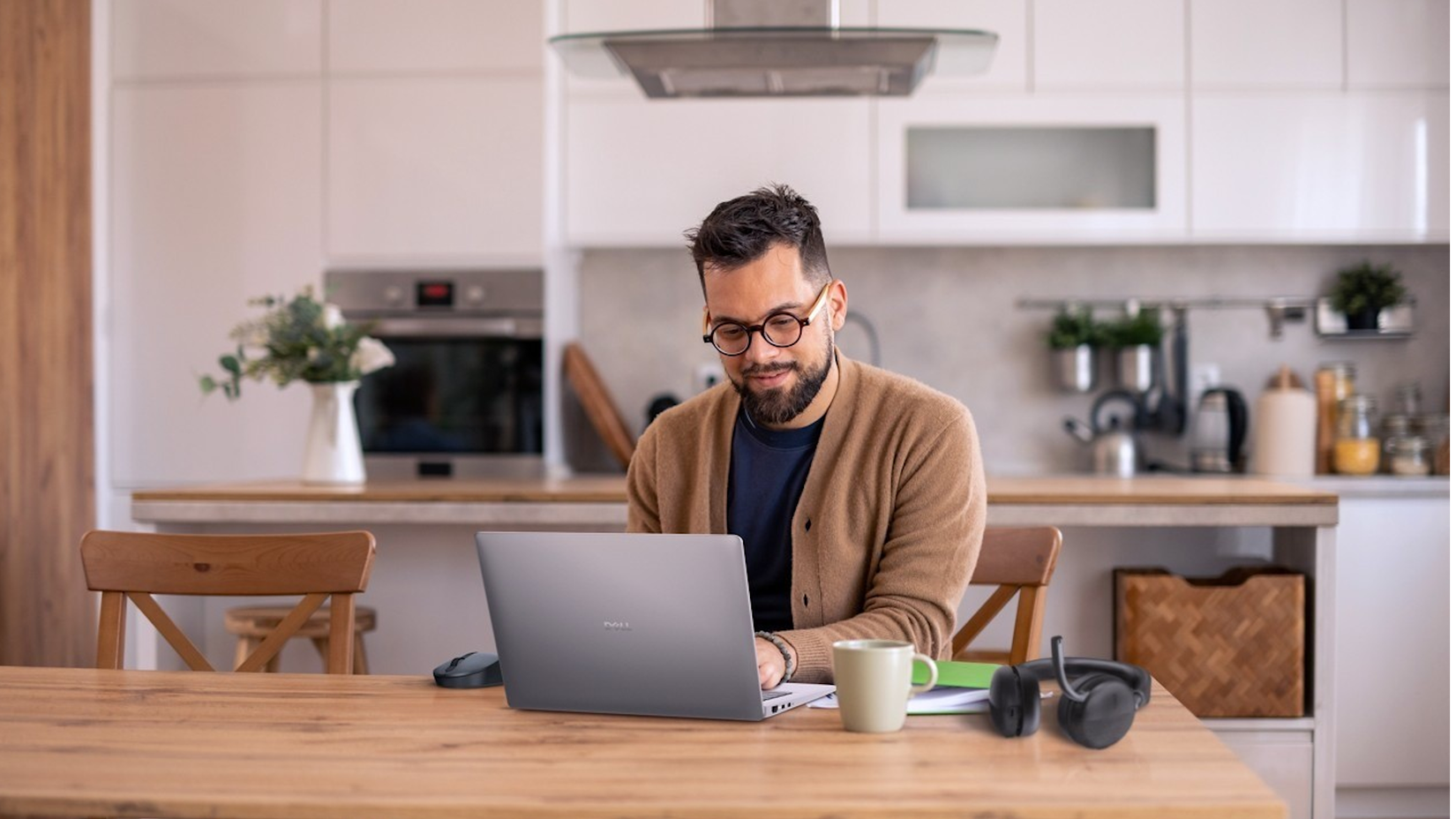 A man working on his Dell laptop at his kitchen table