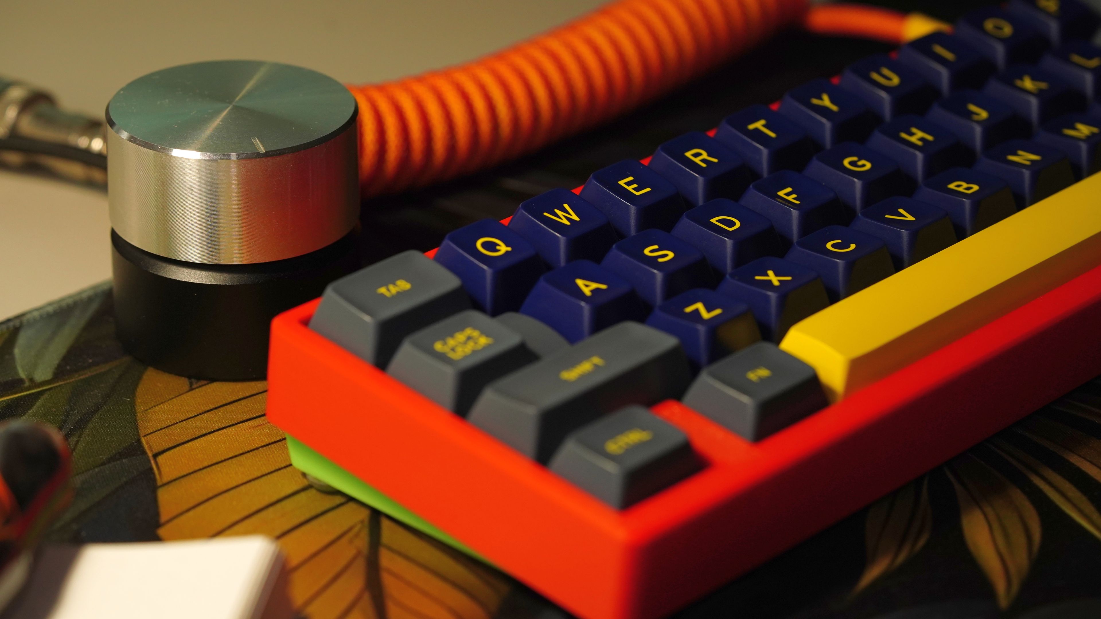 A knob sitting beside a red and blue keyboard
