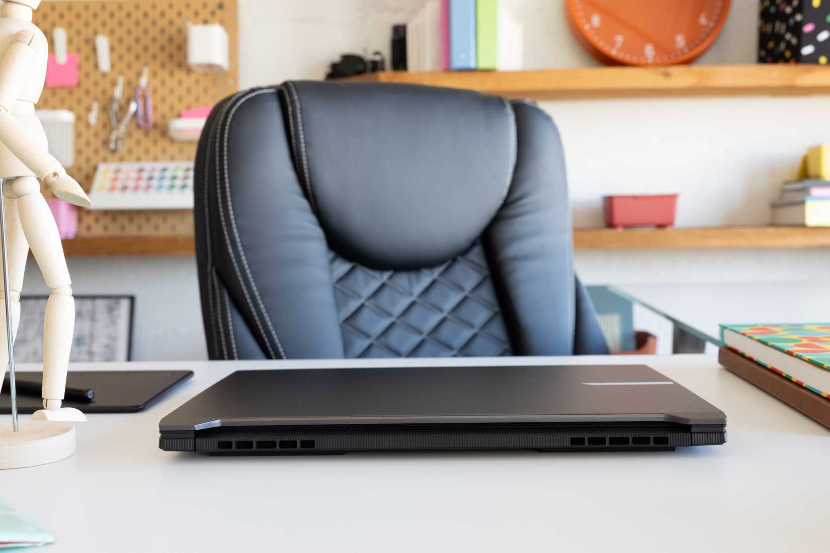 GIGABYTE AERO X16, closed and sitting on a table with a desk chair behind it