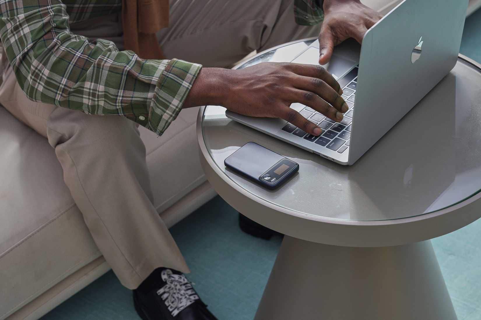 Man working on a laptop with the Comu Action Pro on the table beside him.