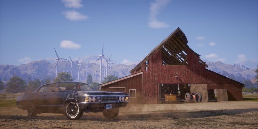 A blue car in front of a red barn