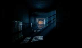 A dark hallway with moonlight beaming through the windows