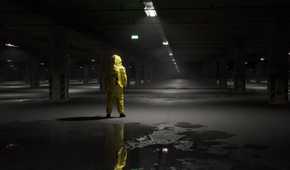 A man in a hazmat suit in a dark underground parking lot