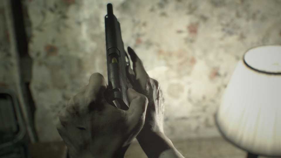 A screenshot of Ethan loading a gun in Resident Evil 7: Biohazard