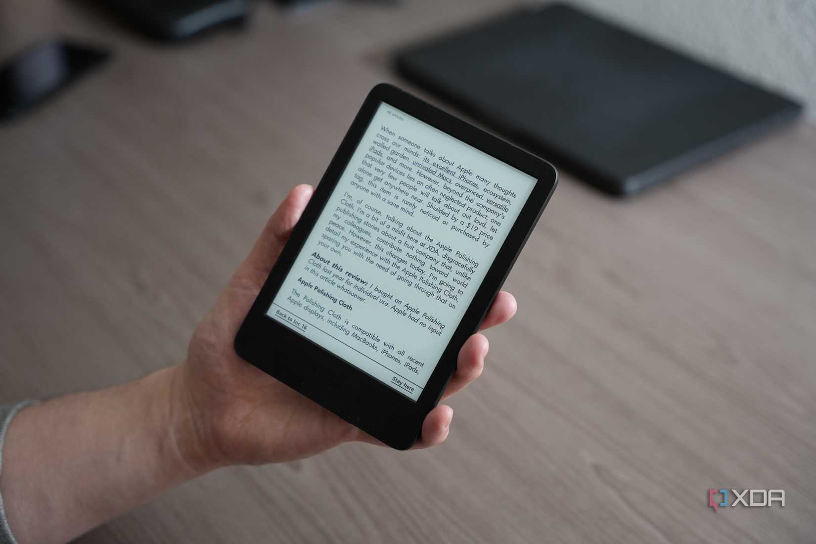 Kindle en mano con artículo del sitio web de XDA en la pantalla
