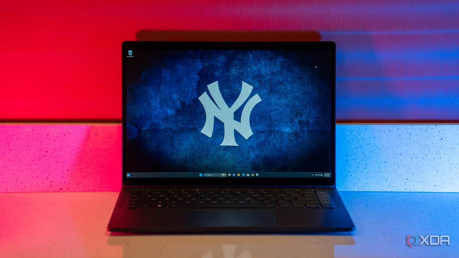 Black laptop with Yankee logo wallpaper, with blue and magenta lighting.